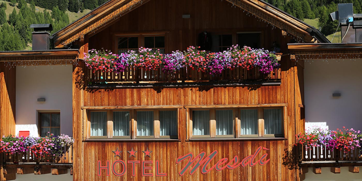 Detail der Holzfassade des Hotels Mesdì mit bunten Blumen auf den Balkonen