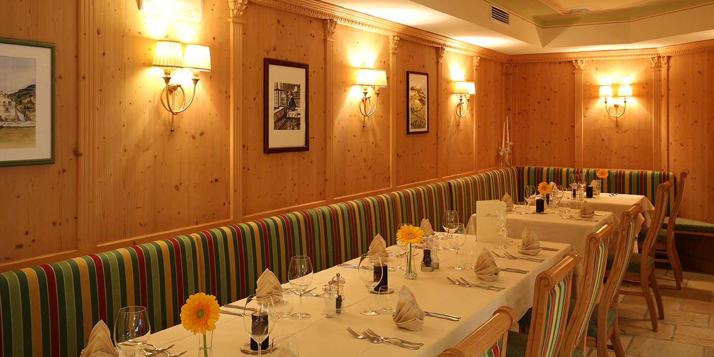 La sala da pranzo dell'Hotel Mesdì con le pareti in legno, i tavoli apparecchiati e i cuscini colorati