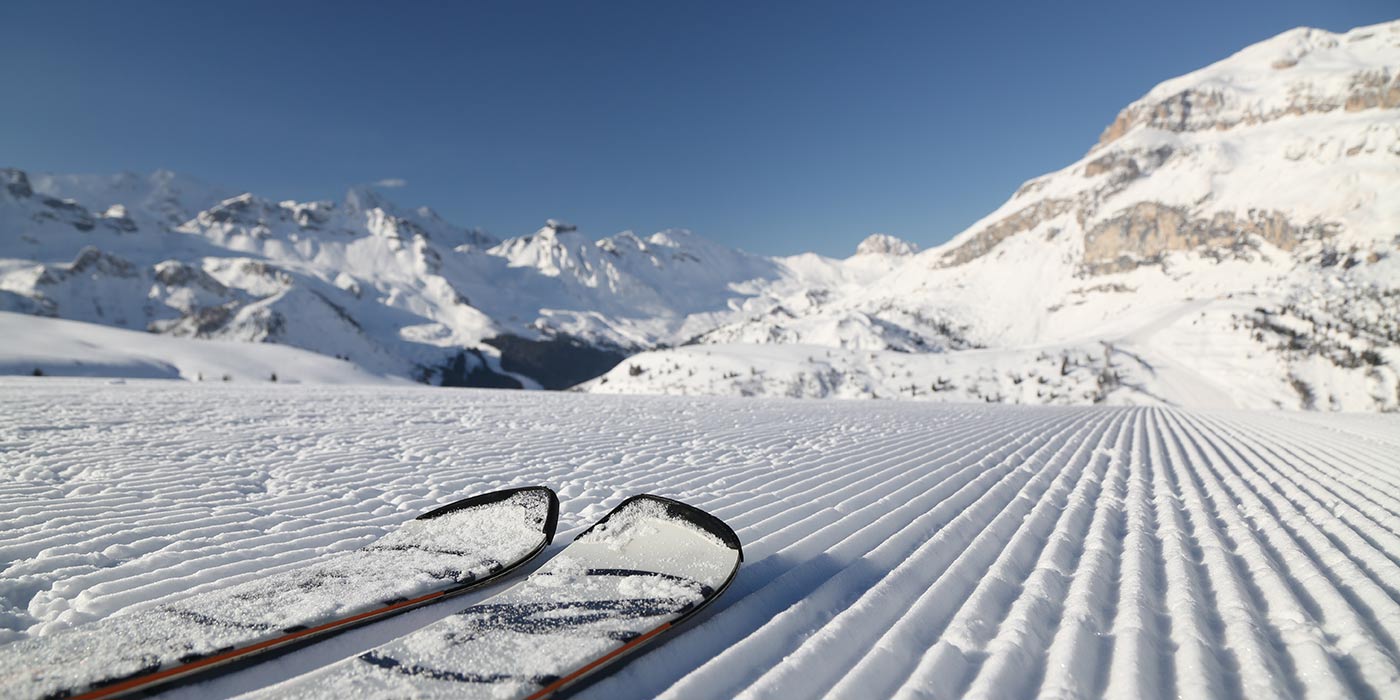 A couple of ski on a snow track with the Dolomites on the background