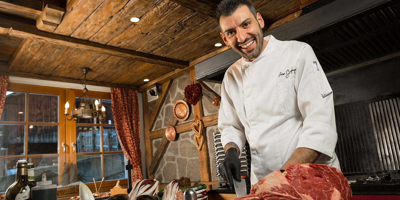 Lo chef del Mesdì in cucina sorride mentre affetta il prosciutto crudo