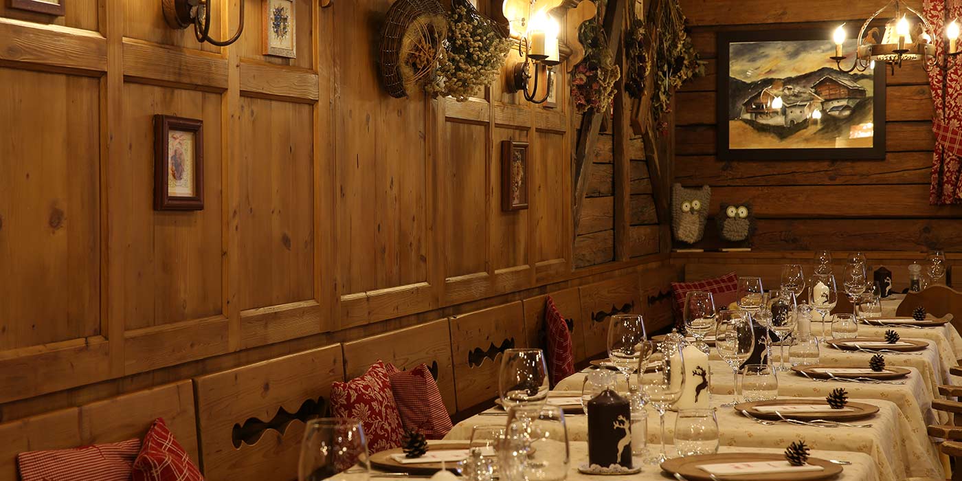 La sala del ristorante all'Hotel Mesdì, interamente decorata in legno con i tavoli apparecchiati e i cuscini rossi