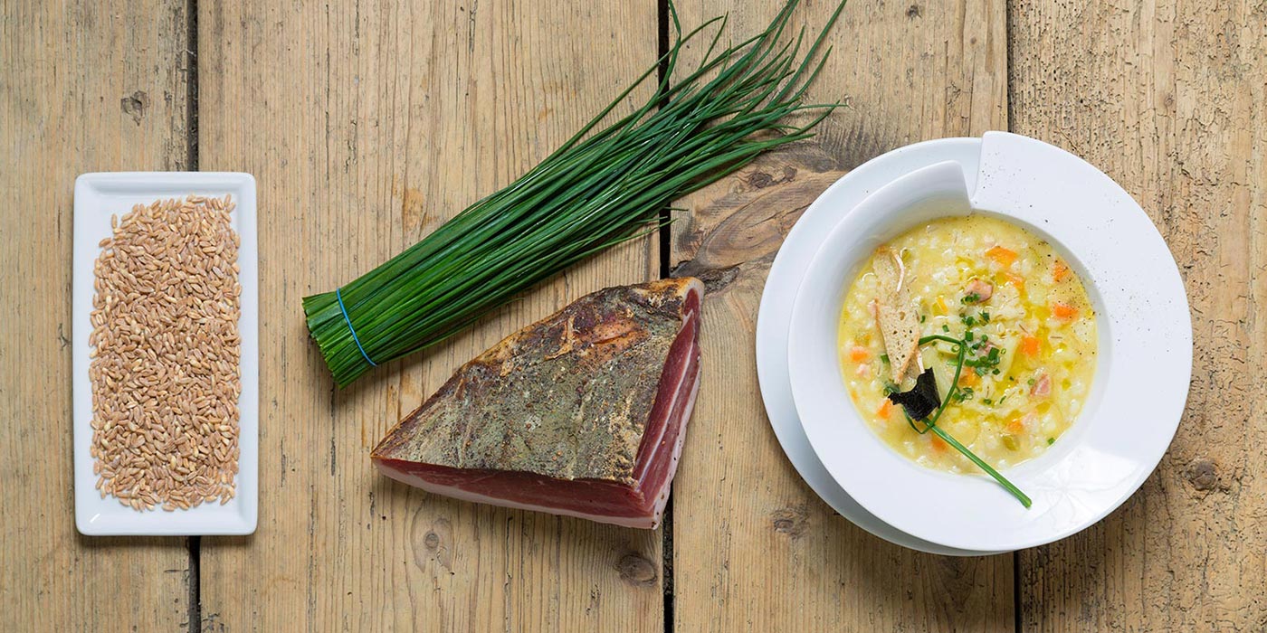 Piatto di zuppa d'orzo con gli ingredienti di base a fianco